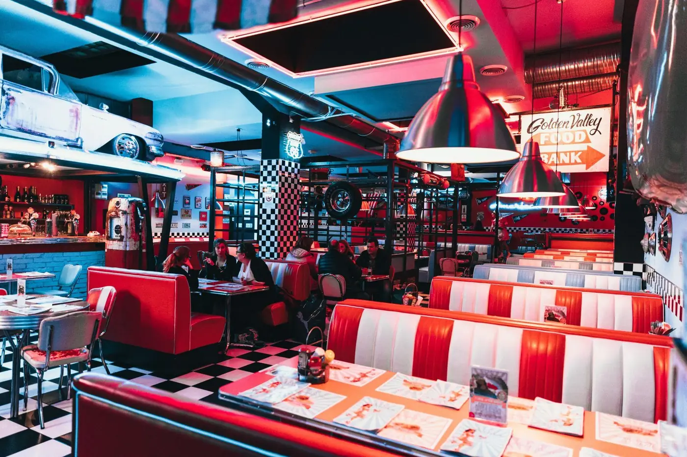 A busy retro diner with red booths and neon signage
