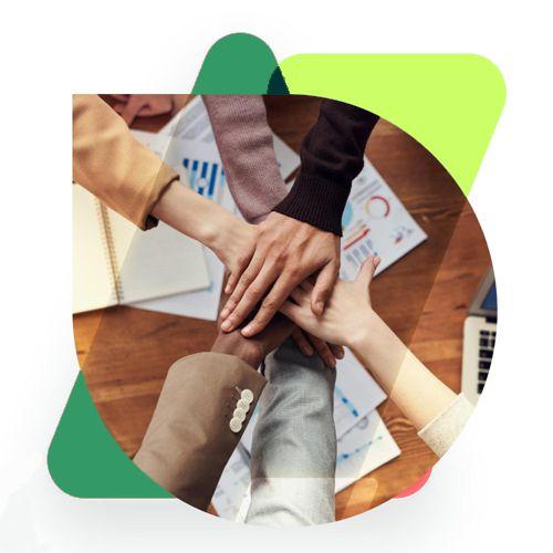 Four colleagues stacking their hands together over a table of printed reports